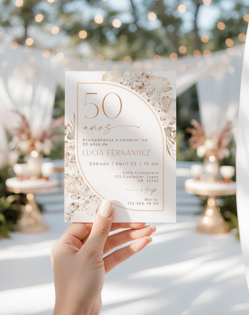 May include: A rectangular invitation card featuring a gold-toned arch design, dried floral accents, and the text 50 a&ntilde;os, Acomp&aacute;&ntilde;anos a celebrar los 50 a&ntilde;os de LUCIA FERNANDEZ, S&aacute;bado, Abril 22, 10 am, Calle Cualquiera 123, CP 12345, rsvp, Maria 123-456-78-90.