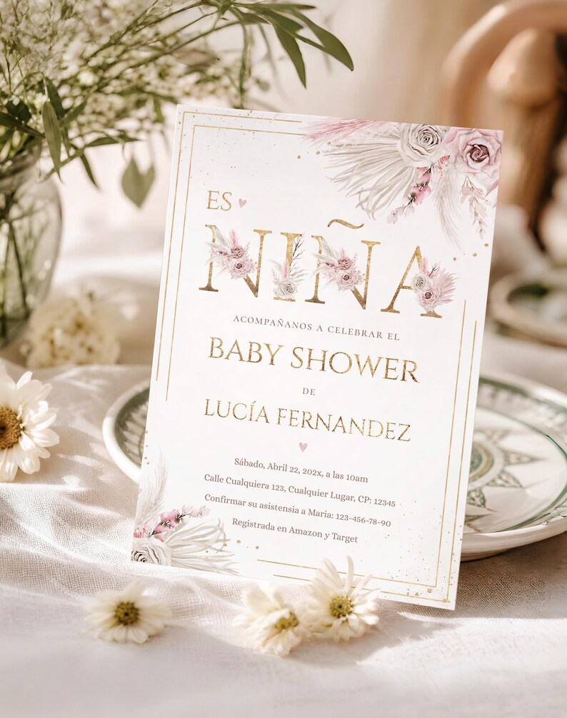 Pu&ograve; includere: Un invito per un baby shower con scritte dorate e un design floreale. L'invito recita "ES NI&Ntilde;A BABY SHOWER DE LUC&Iacute;A FERNANDEZ" con i dettagli dell'evento. L'invito &egrave; su sfondo bianco con accenti floreali.