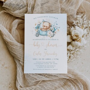 May include: A blue and white baby shower invitation with a cartoon teddy bear driving a blue car. The invitation says "No podemos esperar" and "baby shower de Carlos Fernandez". The date and time of the shower are listed as "Sab 24 de Abril | 3 PM". The address is "Calle Cualquiera 123, Cualquier Lugar. CP: 12345". The invitation also includes a phone number to RSVP and states that the shower is registered at Amazon and Target.