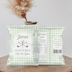 May include: Two light green gingham-patterned snack bags with text. One bag says "James" with a golf-themed logo and "Mastered His 1st Year." The other bag has "Nutrition Facts" and "Thank You for coming and celebrating my 1st Birthday with me!"
