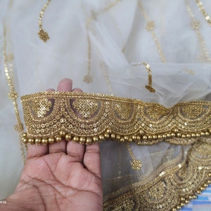 May include: White sheer fabric with a gold embroidered border. The border features a row of gold beads and a scalloped design.