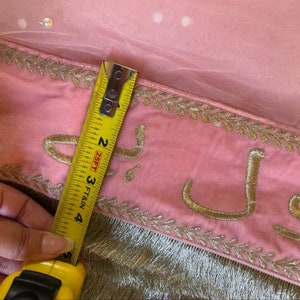 May include: Pink fabric with gold embroidery and a measuring tape showing 4 inches. The fabric has a delicate, sheer overlay.