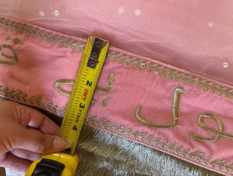 May include: Pink fabric with gold embroidery and a measuring tape showing 4 inches. The fabric has a delicate, sheer overlay.