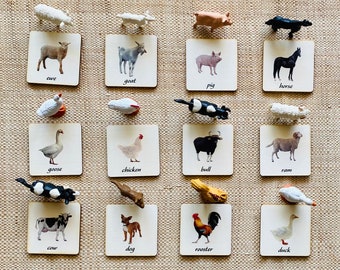 May include: A set of 16 wooden cards with images of farm animals and their names. The cards are arranged in a grid of four rows and four columns. Each card features a different animal, including a cow, pig, horse, sheep, goat, chicken, goose, duck, rooster, bull, ram, and dog.