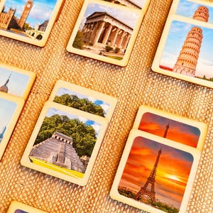 May include: A collection of wooden coasters displaying famous landmarks, including the Eiffel Tower, Big Ben, and the Leaning Tower of Pisa. Each coaster has a square shape with a light wood border and a colourful image of a well-known location.