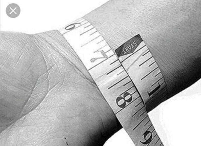 May include: A close-up of a white measuring tape wrapped around a person's wrist. The tape reads "START" and shows measurements in inches.