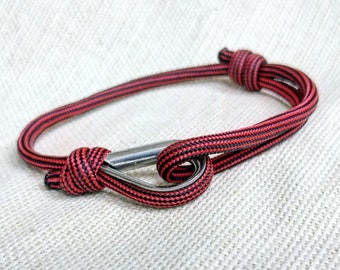 May include: A red and black striped rope bracelet with a silver metal clasp.