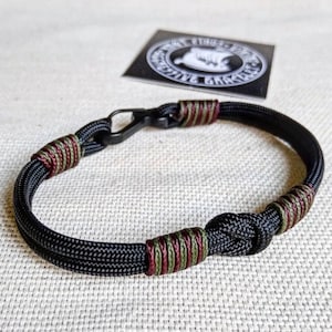 Descargando camping. Brazalete militar fino de paracord y mosquetón para hombre. Estilo militar.