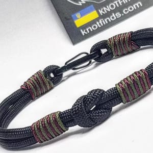 キャンプでの荷降ろし。パラコードとカラビナで作った、男性用の薄型ミリタリーブレスレット。アーミースタイル。