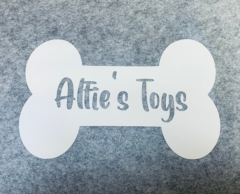 Op de afbeelding: Een wit bord in de vorm van een bot met de tekst "Alfie's Toys" in een cursief schrift.