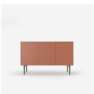 May include: A three-door cabinet with a terracotta finish and black metal legs. The cabinet has a modern design and is perfect for storing items in a living room or dining room.