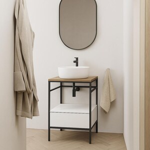 Puede incluir: Un lavabo de baño de cerámica blanca con un grifo negro se asienta sobre una encimera de madera. El lavabo está montado en un soporte de metal negro con un cajón blanco. Una toalla cuelga de un gancho en la pared detrás del lavabo.