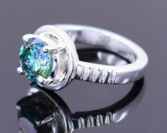 May include: A silver ring with a large, round, blue and green gemstone set in a prong setting. The band of the ring has a textured design.