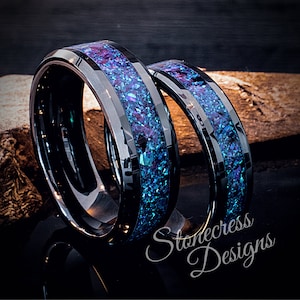 May include: Two black tungsten carbide rings with a blue and purple iridescent inlay. The rings are stacked on top of each other. The text "Stonecress Designs" is visible in the lower right corner of the image.