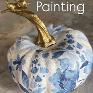 Peut inclure: Une citrouille d&eacute;corative avec un motif floral blanc et bleu. La tige est dor&eacute;e et le mot "Painting" est &eacute;crit en blanc. Parfait pour la d&eacute;coration d'automne.