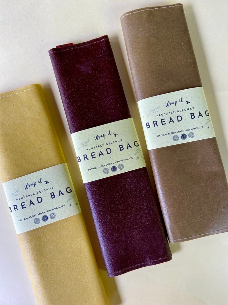 Pu&ograve; includere: Tre sacchetti per il pane riutilizzabili in cera d'api nei toni del giallo, bordeaux e marrone. Ogni sacchetto &egrave; arrotolato e presenta un'etichetta bianca con il testo "Wrap it BREAD BAG", "REUSABLE BEESWAX" e "NATURAL ALTERNATIVE 100% HANDMADE".