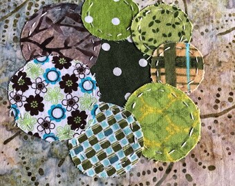 Può includere: Una composizione circolare di cerchi di tessuto colorati. I cerchi presentano vari motivi, tra cui floreali, a pois e a quadri, cuciti su uno sfondo a fantasia. La tavolozza dei colori comprende verde, blu, marrone e bianco.