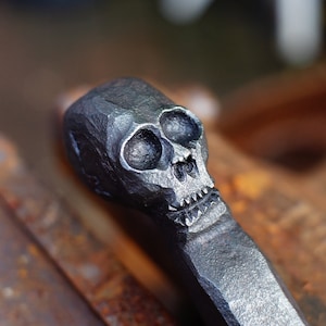 Forged fire poker with skull head.
