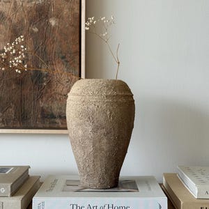 May include: A set of three ceramic mugs with a speckled, matte finish. The mugs are in cream, light grey, and dark grey. Each mug has a simple, minimalist design, ideal for coffee or tea.