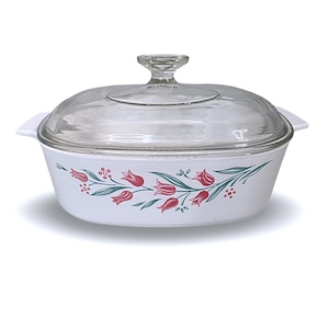 May include: White casserole dish with a clear glass lid. The dish features a floral design of red tulips and green leaves. The lid has a clear glass handle. The dish has two white handles on either side.