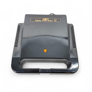May include: A black Salton Belgian Waffle Maker with a rectangular design. The waffle maker has a handle and a small orange light. The text "Salton Belgian Waffle Maker" is printed on the top.