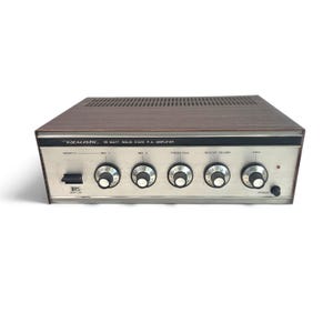 May include: A Realistic 35 Watt Solid State P.A. Amplifier with a wood-grain top and a silver front panel. The unit features five black control knobs labeled Priority, Mic 1, Mic 2, Phono/Aux, Master Volume, and Tone, plus a power switch.