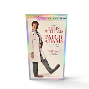 May include: A VHS tape of the film Patch Adams, featuring Robin Williams in a white doctor's coat and oversized red shoes. The cover includes the text Universal Special Edition, Robin Williams, Patch Adams, Based on a True Story, and Brilliant!