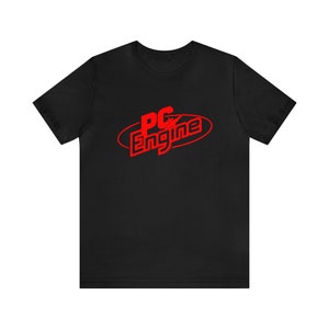 May include: Black t-shirt with a red oval design that says "PC Engine" in a stylized font. The shirt is made of a soft material and has short sleeves and a crew neck.