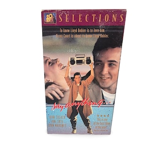 May include: A VHS tape of the movie "Say Anything..." featuring John Cusack. The cover has a photo of the main characters and the title in a stylized font. The tape is in a cardboard box.