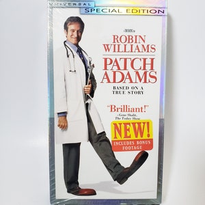 May include: Sealed VHS tape of the movie "Patch Adams" starring Robin Williams. The cover features Williams in a doctor's coat, with the film's title in red and white. Includes bonus footage.