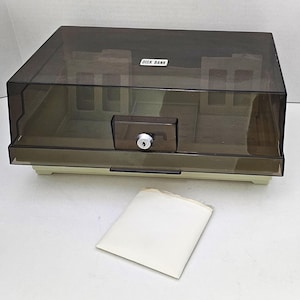 May include: A clear plastic storage box with a beige base and a lock. The box has a label that reads "Disk Bank".