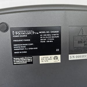 May include: A gray Emerson Research radio with a black label that reads "Research TM MODEL NO.: CKS2020", "POWER SOURCE", "FREQUENCY RANGE", "EMERSON RADIO CORP.", "9 ENTIN ROAD", "PARSIPPANY, N.J. 07054-0430", "MADE IN CHINA", "AC 120V 60Hz 6 WATTS", "DC 3V (CLOCK BACKUP)", "AM 530-1710 kHz", "FM 88-108 MHz", "LISTED BY ETL TO ANSI/ UL 1270", "ZZ", "CAUTION RISK OF ELECTRIC SHOCK DO NOT OPEN", "WARNING SHOCK HAZARD-DO NOT REMOVE COVER", "S/N:00609203LS".