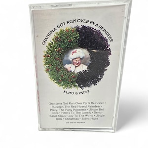 May include: A clear cassette tape with the title "Grandma Got Run Over By A Reindeer." The cover features a festive wreath design with a portrait of a person wearing a Christmas hat. The artist is Elmo & Patsy. Song titles are listed below.