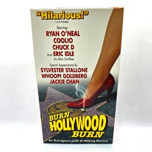 May include: A VHS tape cover for the movie "Burn Hollywood Burn" featuring a woman's leg in a red high heel shoe stepping on a star on the Hollywood Walk of Fame. The cover features the movie title and the names of the actors: Ryan O'Neal, Coolio, Chuck D, Eric Idle, Sylvester Stallone, Whoopi Goldberg, and Jackie Chan.