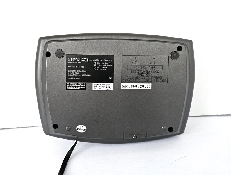 May include: A gray clock radio with a black power cord. The clock radio has a digital display, AM/FM radio, and a clock backup feature. The text on the back of the clock radio reads "Research Model No. CKSS200 Power Source AC 120V 60Hz 8 Watts DC 3V (Clock Backup) Frequency Range AM 530 - 1710 kHz FM 88 - 108 MHz Listed by ETL 101720", and "Caution Risk of Electric Shock Do Not Open S/N:00609203LS".
