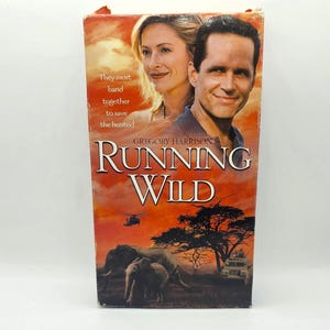 May include: A VHS video cassette cover with a red, orange, and yellow sunset background. The title "RUNNING WILD" is in large white letters. The cover features a man and woman standing in front of a herd of elephants. The text "They must band together to save the hunted" is in white letters on the left side of the cover.