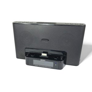 May include: Black Sony personal audio docking system with a digital display. The system has a rectangular shape with a speaker grill and several buttons on top. The docking station is in the front and has the Sony logo.