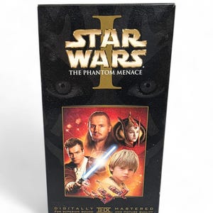 May include: A black VHS tape box for Star Wars: The Phantom Menace. The box features the Star Wars logo in gold, the film title, and images of characters. The bottom of the box reads "Digitally Mastered for Superior Sound and Picture Quality."