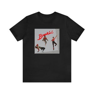 May include: Black t-shirt with a graphic of the movie "Breakin'" featuring three dancers in red, black, and white clothing against a gray background with a black and white checkered border.