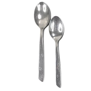 May include: Two vintage silver spoons. The spoons have oval bowls and long handles. The handles are decorated with a floral pattern. The spoons are set against a white background.