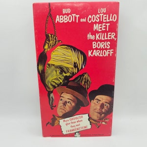 May include: A red and white vintage movie poster featuring Bud Abbott and Lou Costello with Boris Karloff. The poster reads "Bud Abbott and Lou Costello Meet the Killer, Boris Karloff".