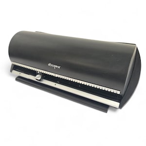 May include: A black discgear CD/DVD label applicator. The device has a curved top and a silver and black measuring guide. The text "discgear" is printed on the top. The applicator is designed to apply labels to CDs and DVDs.