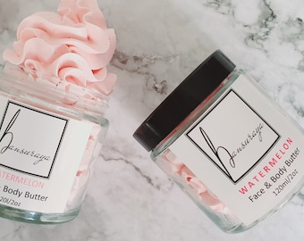 Peut inclure: Deux pots en verre remplis de beurre corporel fouetté rose. Les pots ont des étiquettes blanches avec du texte noir qui indique "Jansuraya Watermelon Face & Body Butter 120ml/4oz".