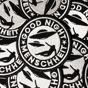 Może przedstawiać: Naszywka haftowana w kolorze czarnym i białym z UFO i tekstem "Good Night Menschheit" w k&oacute;łku.