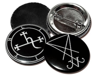 May include: Four black and white button pins with different symbols. The pins are round and have a silver metal backing. The symbols include a cross with a curved line, a triangle with a line through it, and two blank pins.