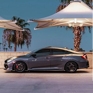 Puede incluir: Un sedán Honda Civic gris estacionado debajo de un dosel blanco. El coche tiene ventanas tintadas y llantas negras.