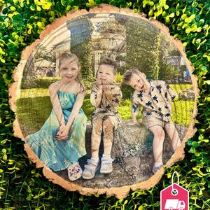 Peut inclure: Une tranche de bois avec une photo imprimée de trois enfants assis sur un tronc d'arbre. Les enfants portent des vêtements décontractés et sourient. La photo est imprimée dans un style vintage.