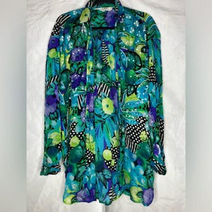 Può includere: Top a maniche lunghe e aperto sul davanti con un vivace motivo floreale nei toni del verde acqua, verde e viola. Il design include motivi di foglie e fiori, con accenti di pois e strisce bianche e nere. Il top è realizzato in tessuto leggero.
