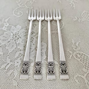 May include: Set of four silver-plated forks with ornate floral designs at the base of the handle.