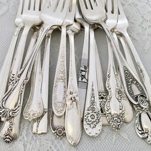 May include: A collection of antique silver forks with ornate, detailed designs. The forks vary in style, showcasing floral patterns, scrollwork, and geometric accents. The silver cutlery is arranged in a close-up shot, highlighting the intricate craftsmanship.